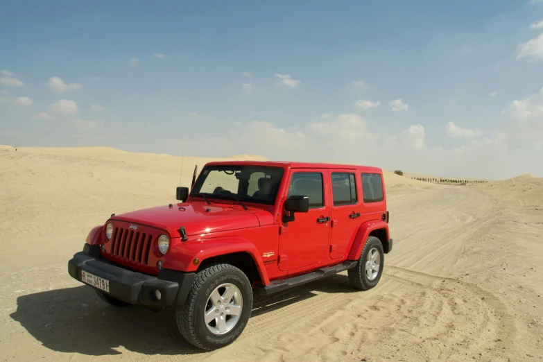 a red jeep is driving down a dirt road