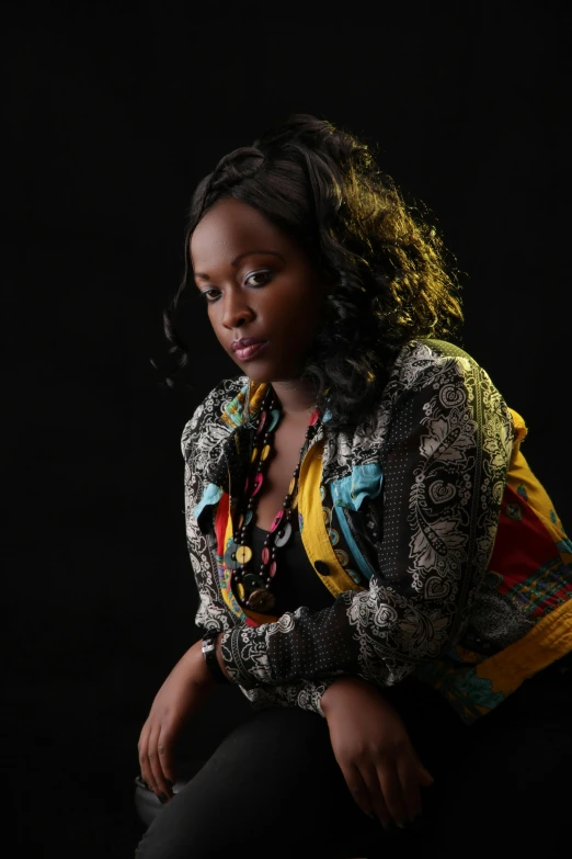 a black girl sitting down on the floor with her hands on her knees