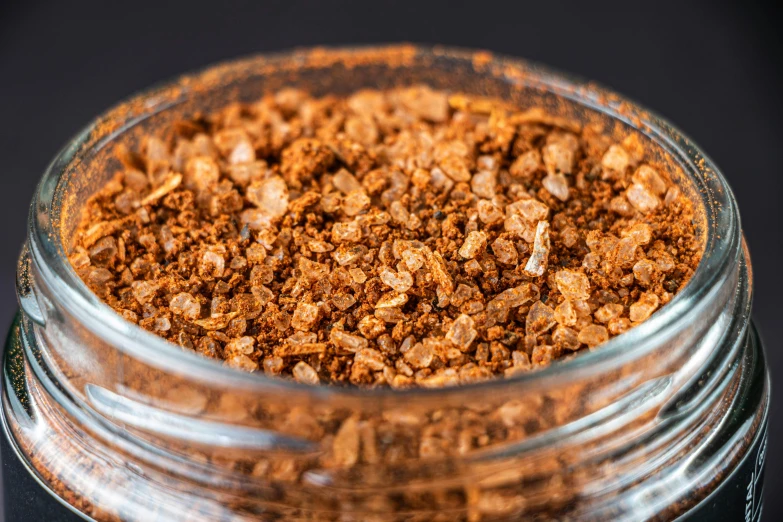 a close up of a glass jar with granola on a black table