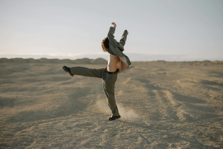 a young man performs a kickbox move on the desert