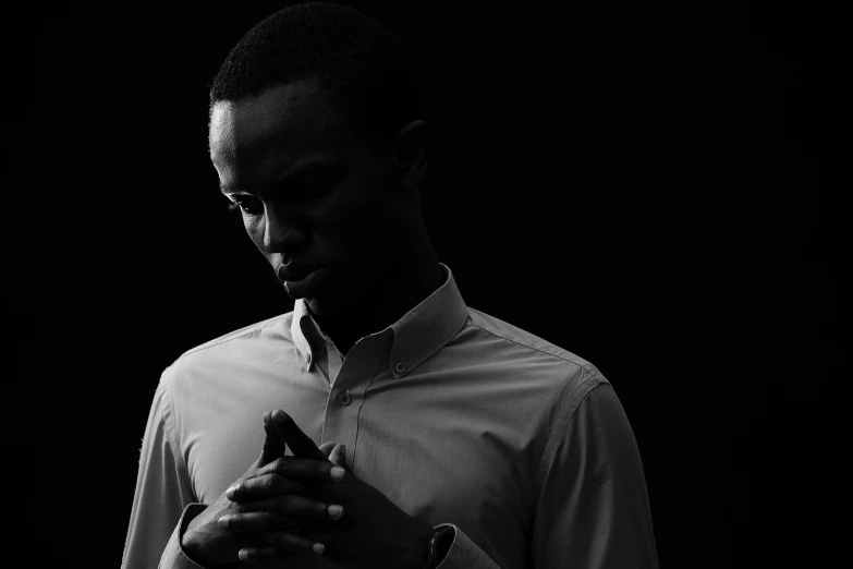 a man looking down at his phone while standing in the dark