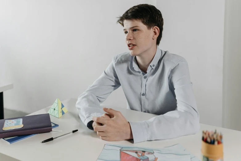 a man sitting at a white desk in a room