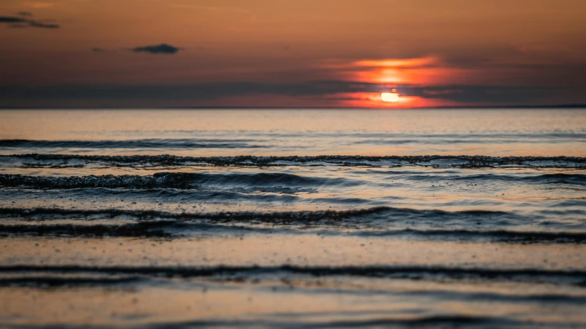 a sunset over the water with a few waves