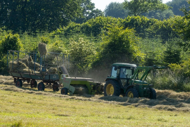 a truck with a load of hay pulling a tractor behind it