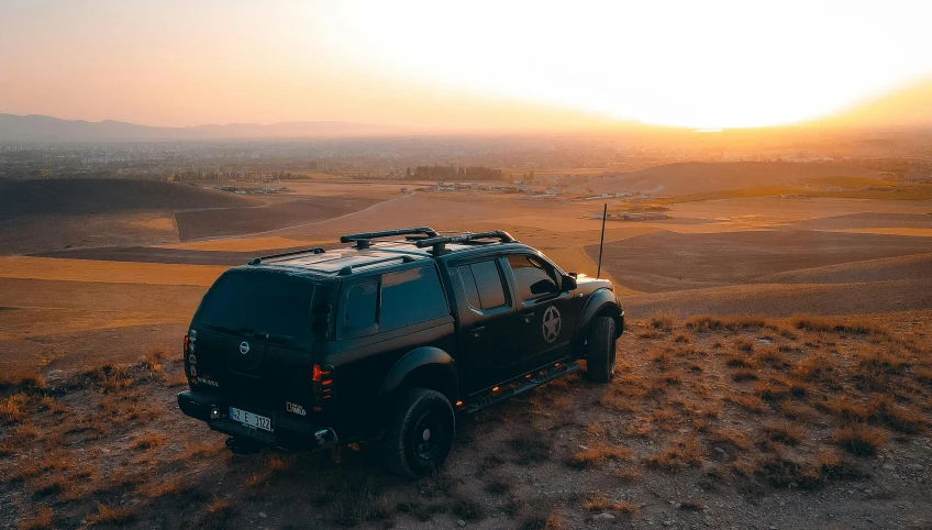 a vehicle sits in the middle of the field during sunset