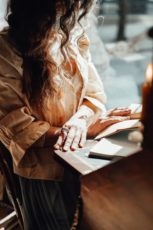 a woman sitting in a chair next to a window holding a book