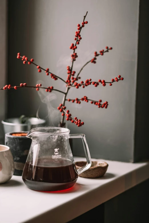 a vase filled with red berries on top of a white table