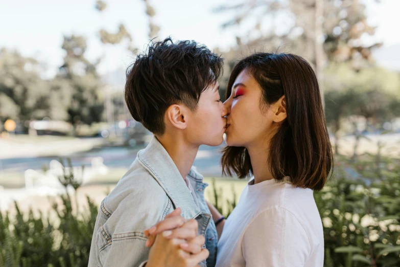 two people kissing each other while in a park