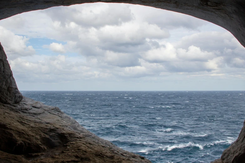 an open cave in the rocks is overlooking the ocean