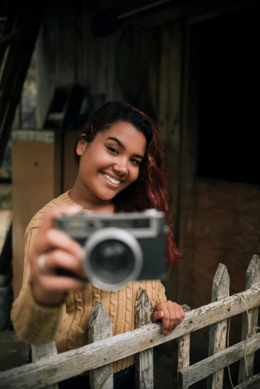 a smiling young woman holding a camera taking a selfie