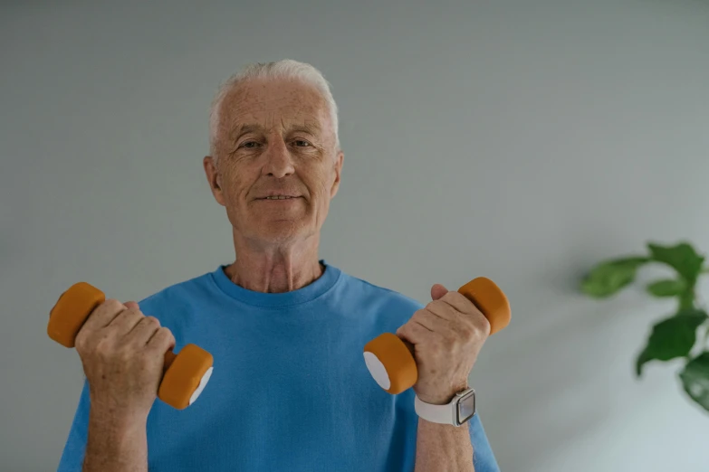 a older man lifting two orange dumbs