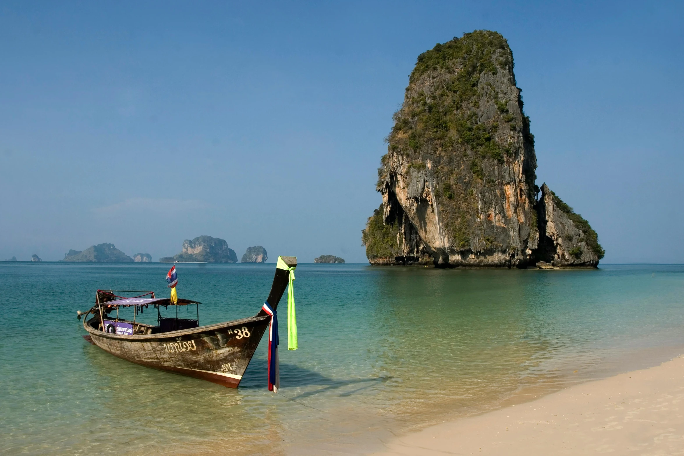 a boat tied to the shore with two people standing on it