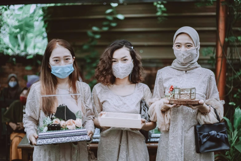 two ladies in masks hold small cakes