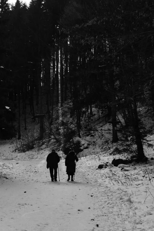 two people walking along side of a snow covered hill