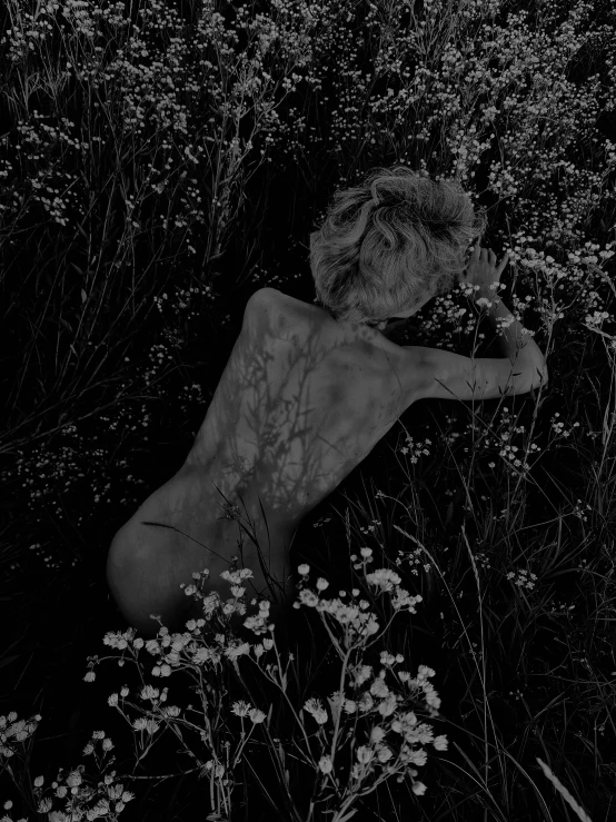 an image of a person covered in ink with flowers and weeds surrounding