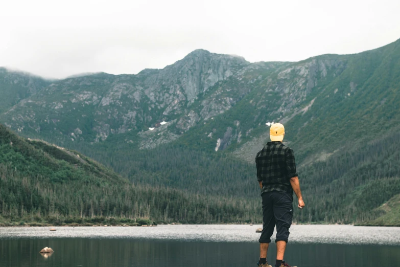 a man standing on the edge of a mountain lake