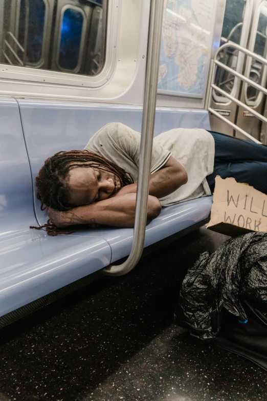 a person asleep on a train with a sign