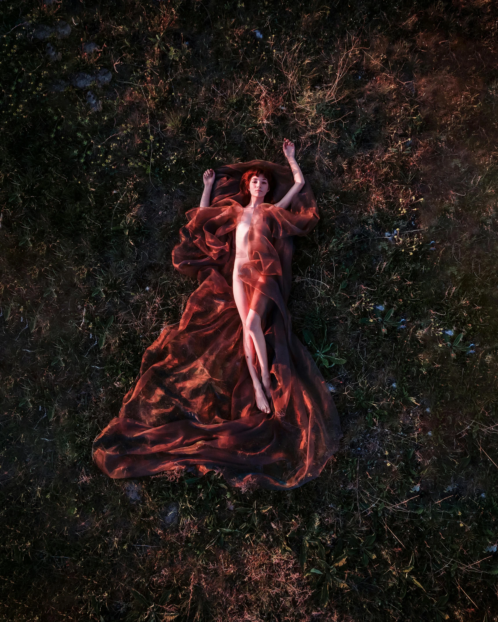 an aerial view of a woman wearing a red flowing dress in the field
