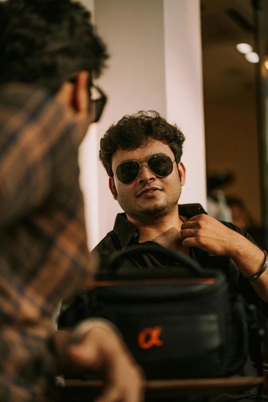 a man in a black shirt is getting his tie adjusted by another man wearing sunglasses