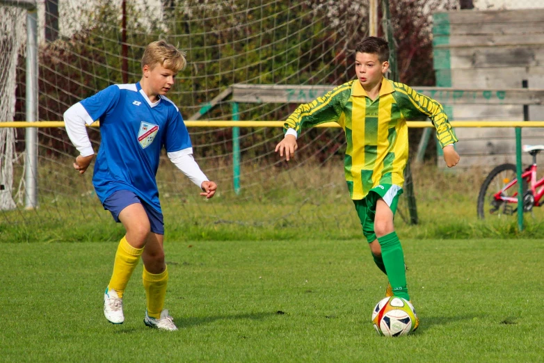 two young men playing soccer on a field