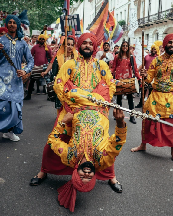 men dressed in orange are holding flags and drums