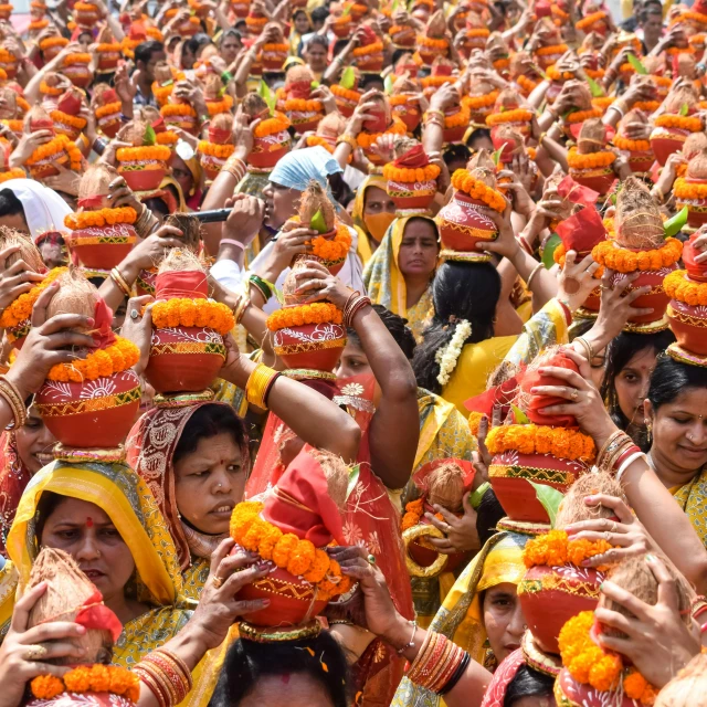 a group of women in traditional dress holding orange objects