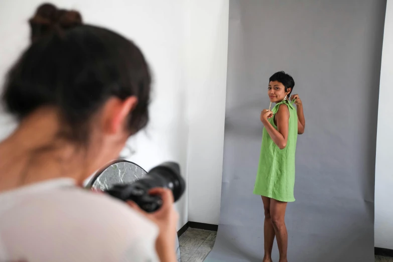 a woman in a green dress is standing in front of a mirror