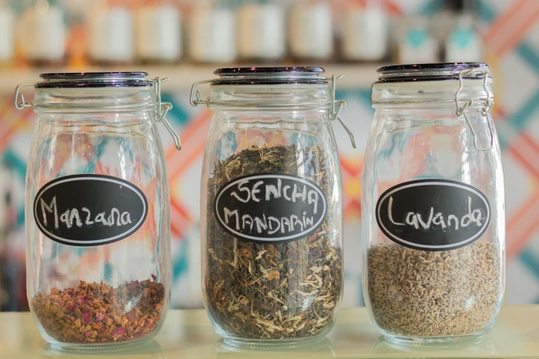 three jars filled with spices are sitting on a table