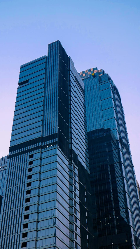 two high rise skyscrs in the city against a bright blue sky