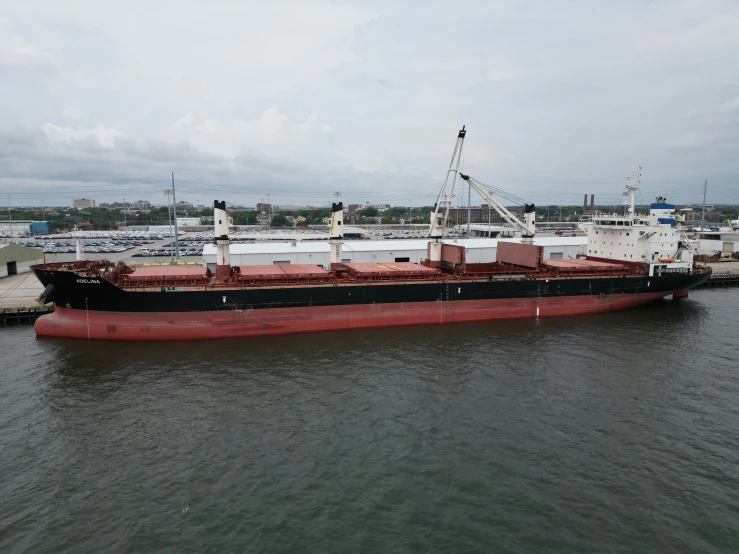 a red boat traveling past a large white building