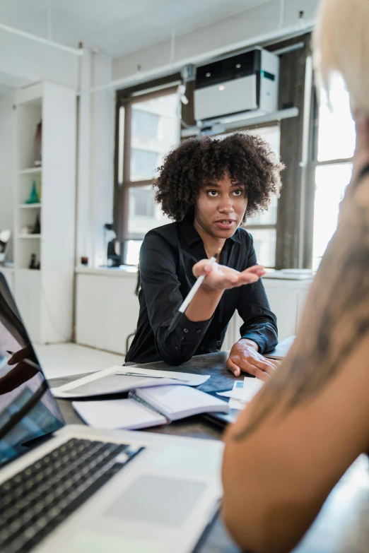 a woman talking to another person near laptops