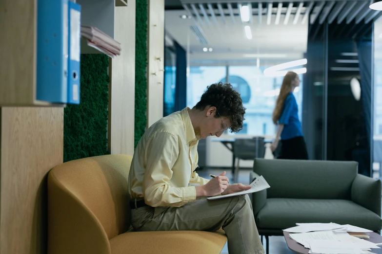 a man sitting on the couch with his hand on his pocket, writing