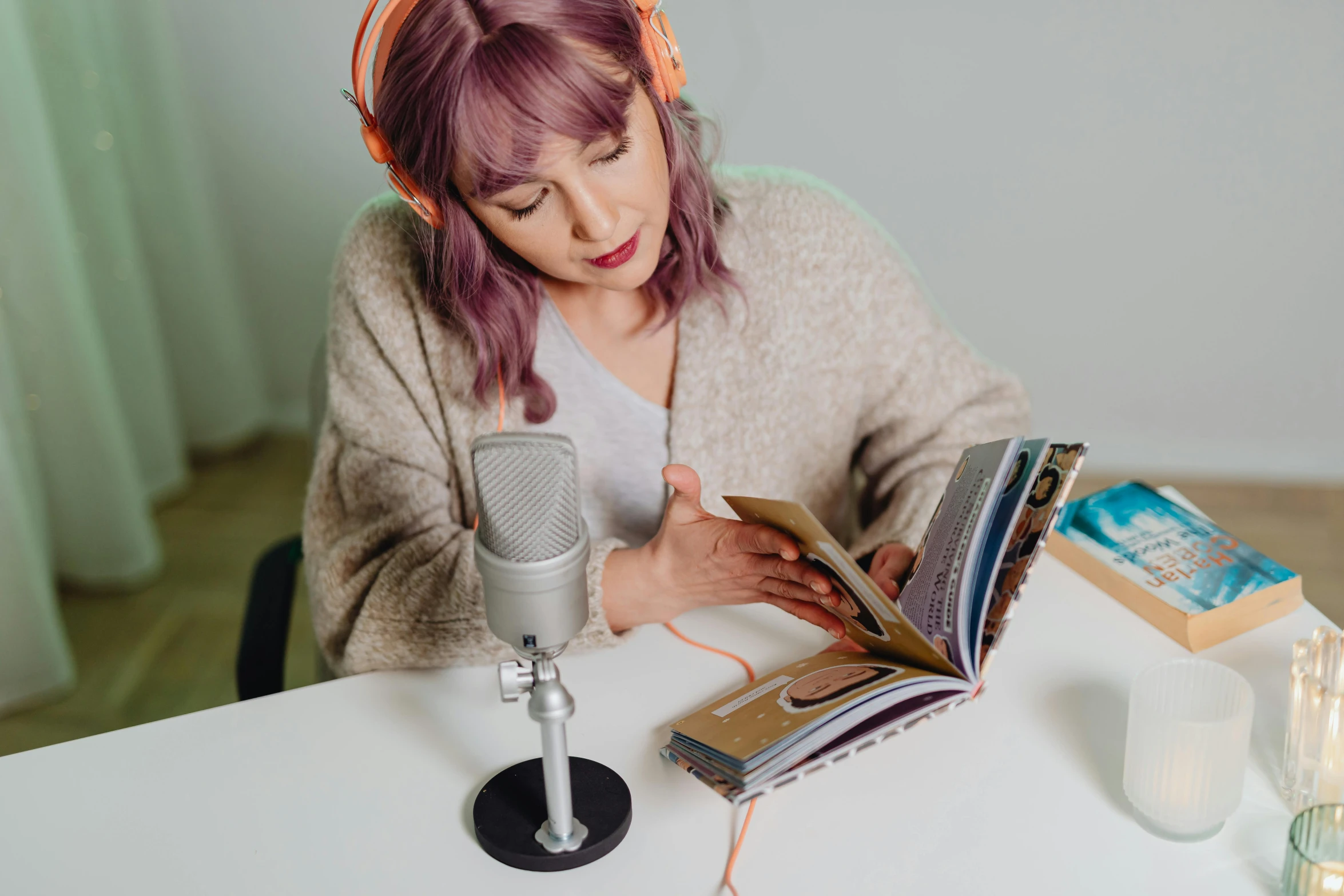 a woman sitting at a table reading a book and drinking coffee