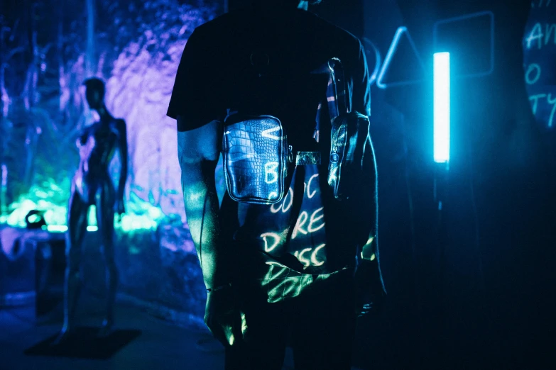 a man standing next to another man and neon lit artwork