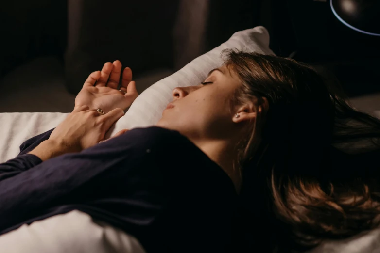 a person laying in bed holding soing to their ear