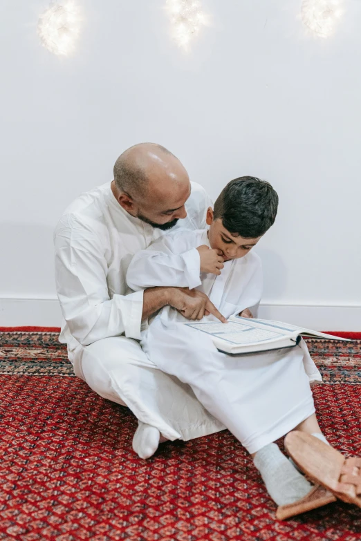 a father is giving his son a hug while sitting on the carpet