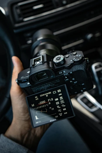 a person holding up a camera in the car