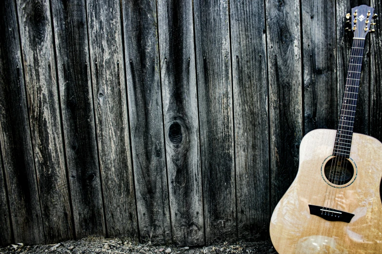 a wooden guitar propped up against a wooden wall