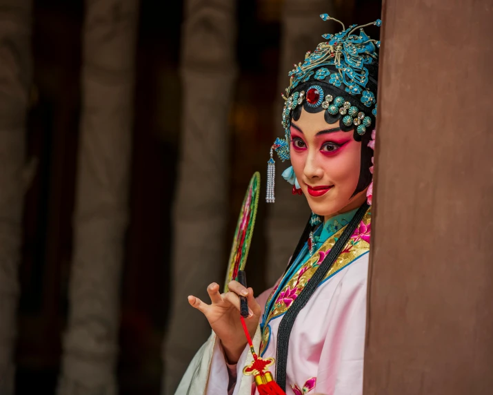 a girl with traditional clothing is holding up a mirror