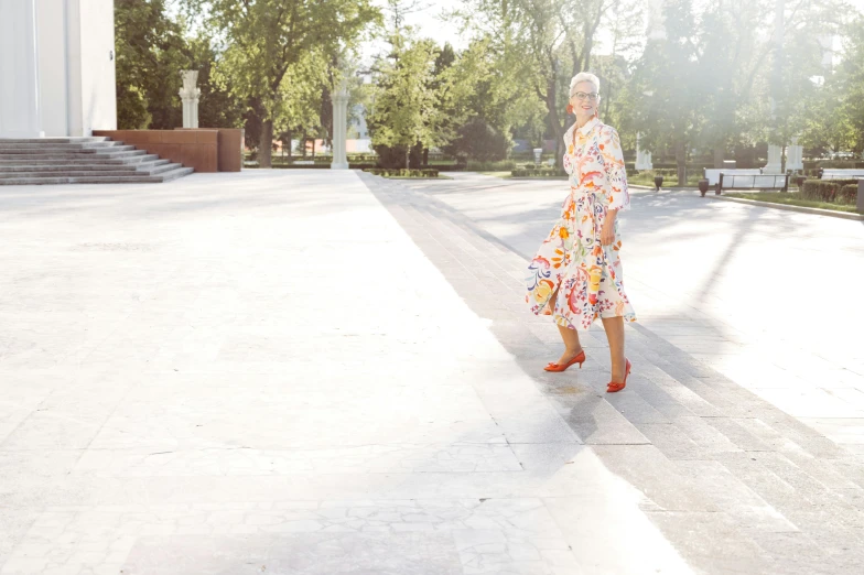 an older woman walking down a paved street wearing a dress