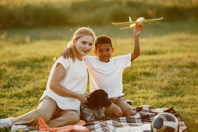 a young couple is sitting on a blanket while holding a toy airplane