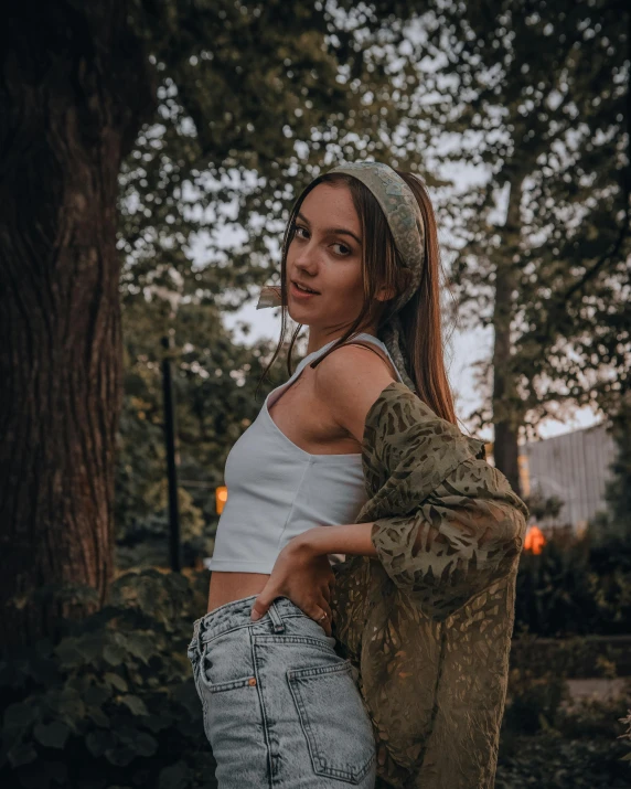 a woman poses by some trees while wearing a crop top