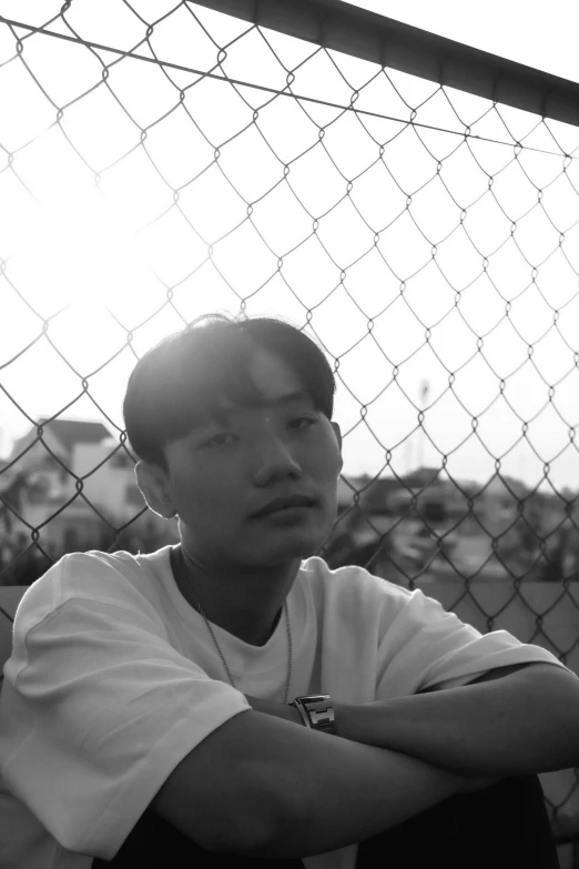 a young man is looking at soing from behind a fence