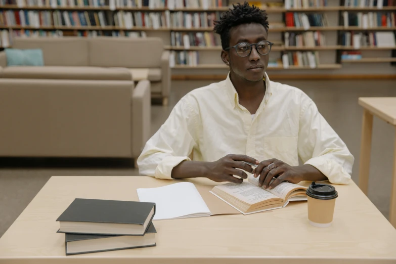 a black male sitting at a table in front of books