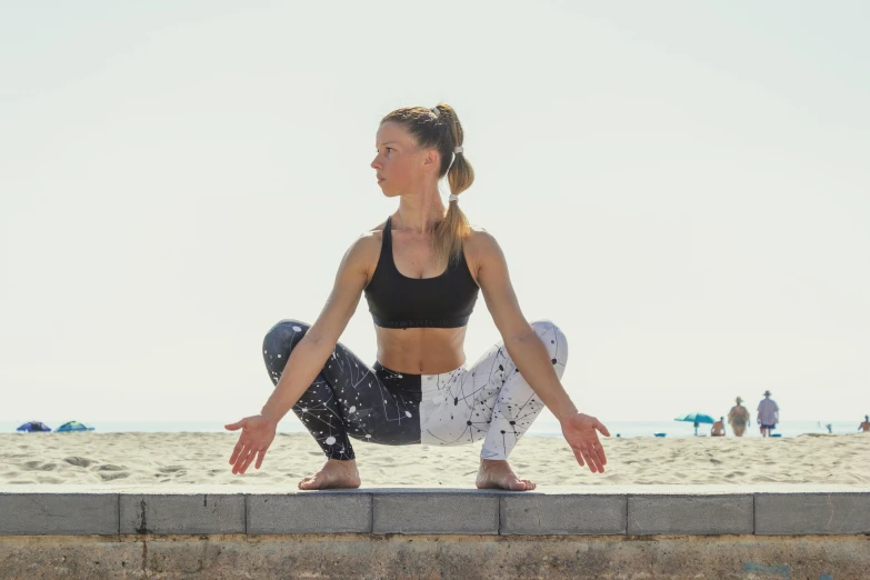 a woman in black top doing yoga near the beach