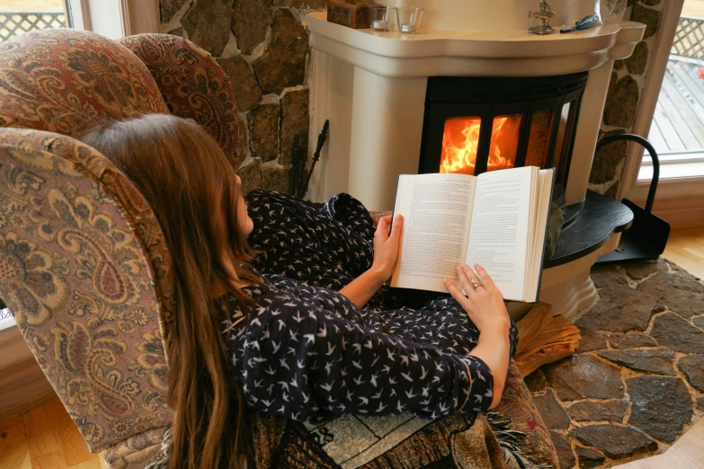 a girl reading in front of the fire place