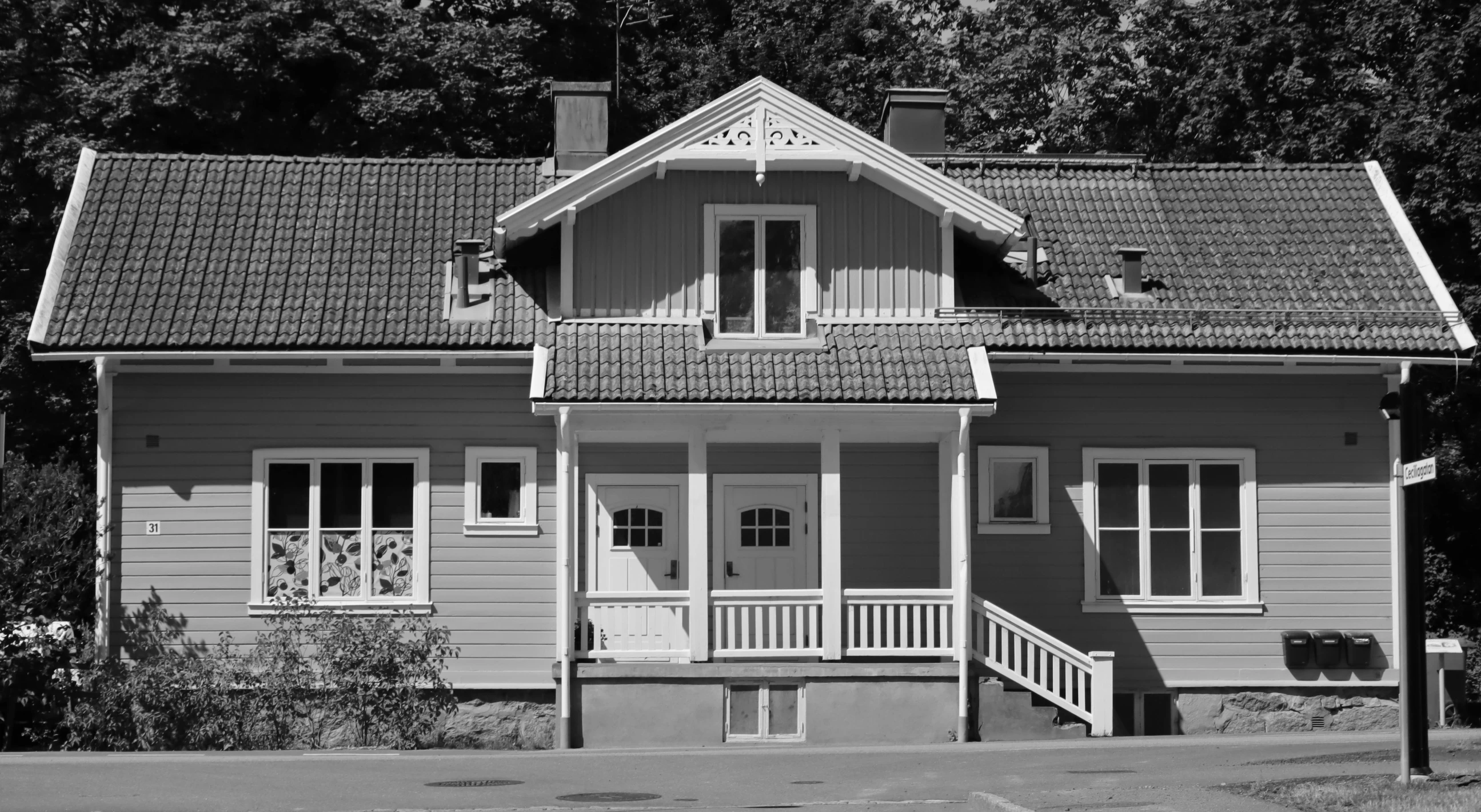 a house sitting on a street corner by some trees