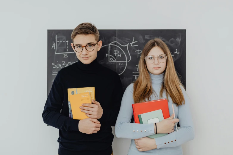 the man and woman are holding folders in front of a chalkboard