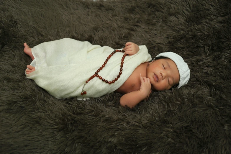 an infant wrapped up and sleeping on a fur rug