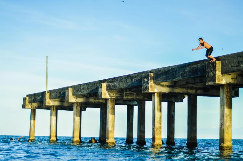 the man is surfing at the bottom of a wooden pier